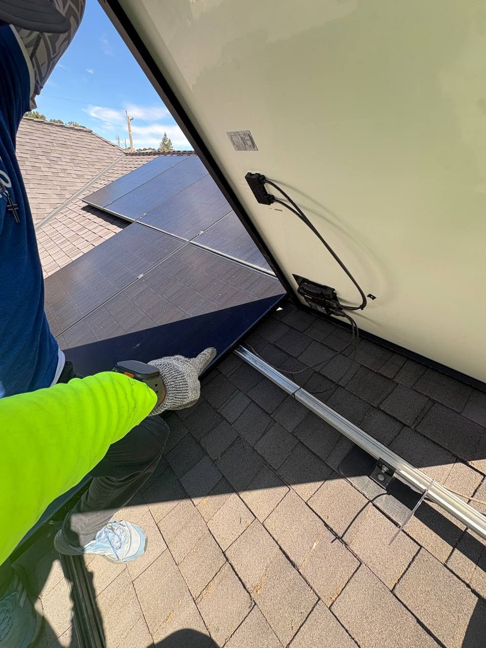Solar installer on rooftop securing module-level electronics and DC leads to the module frame on a residential solar array