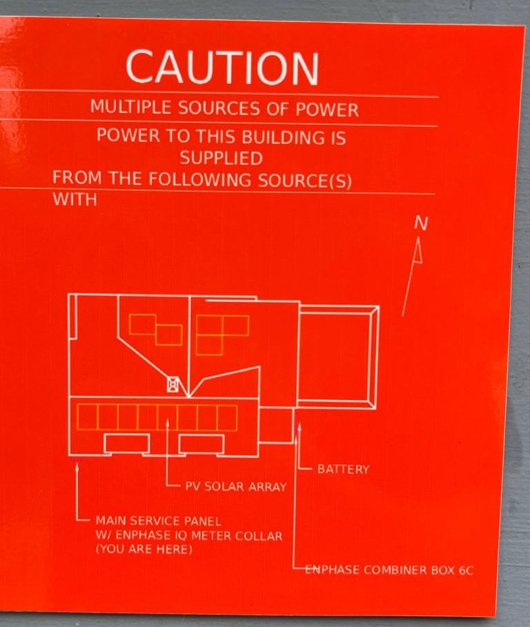 Red caution sign showing a building's electrical power sources: PV solar array, battery, main service panel, and Enphase combiner box