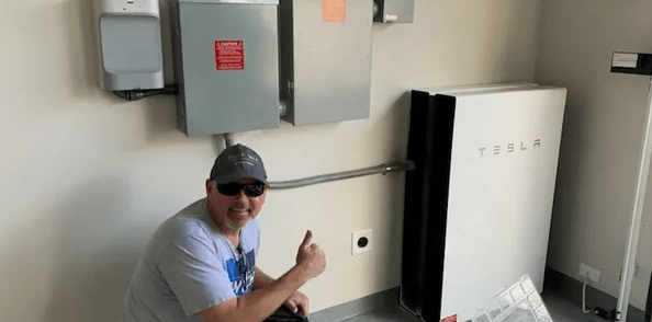 A man giving the thumbs up in front of an electrical panel.